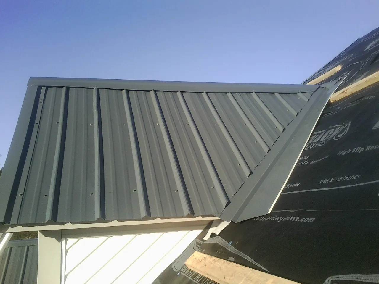 Gray metal roof panels going on over a garage gable in Celina