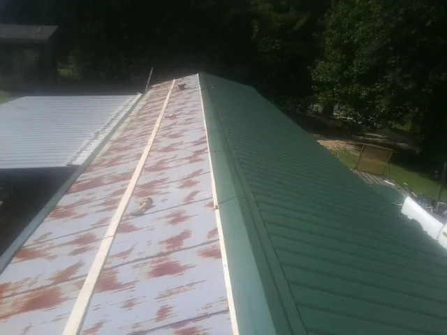 Old rusted panels beside newly installed green metal roofing — Wind Damage Roof Repair by Roofing Brothers in Celina