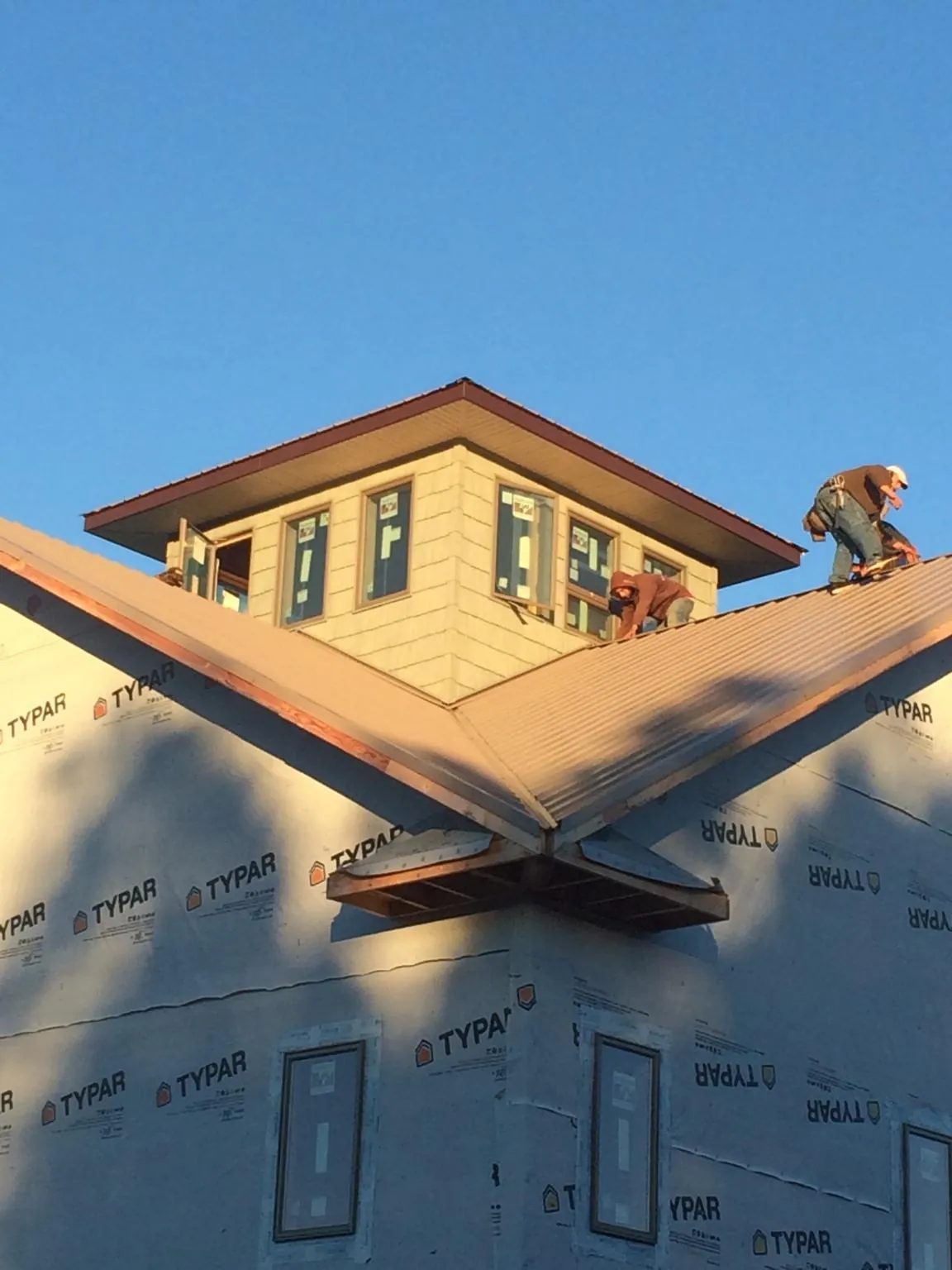 Roofers working around a rooftop cupola on a new metal roof at sunset — Roof Waterproofing in Celina by Roofing Brothers